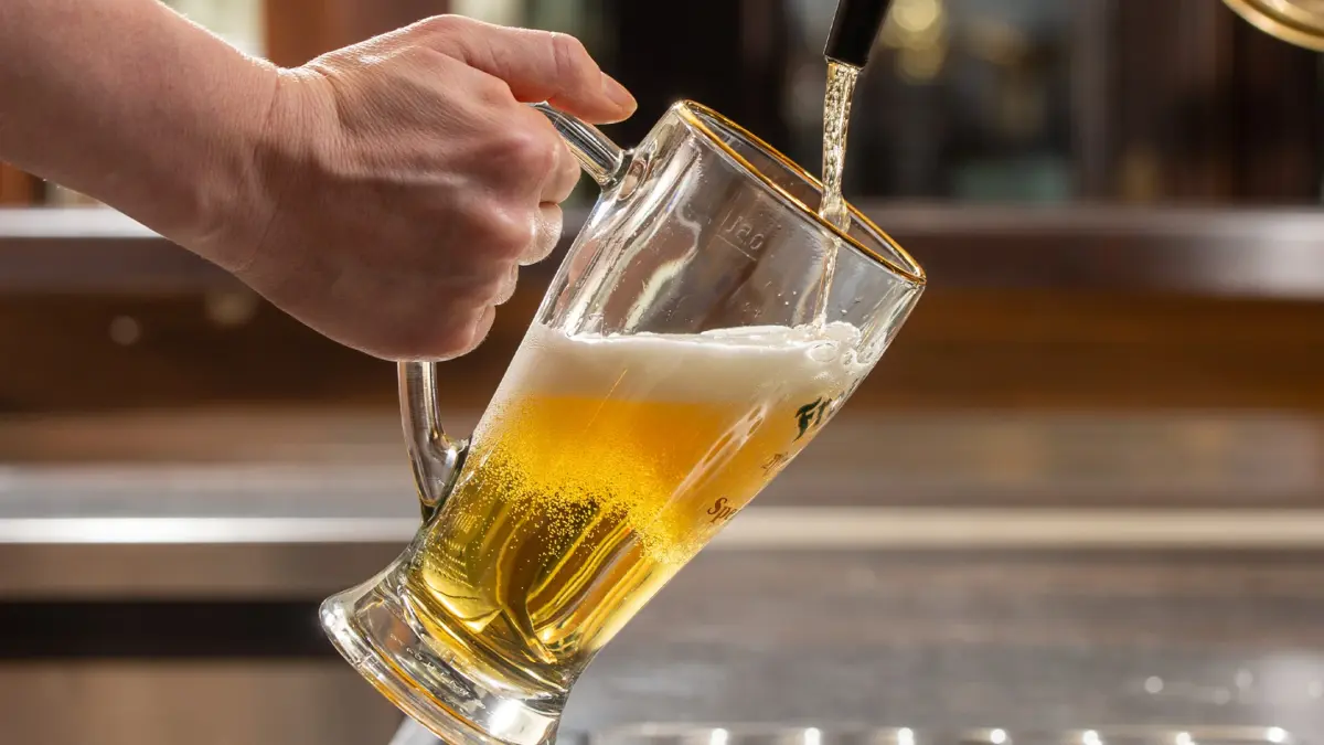 Ein Glas Bier wird gerade von einem Zapfhahn gefüllt, wobei Schaum entsteht.