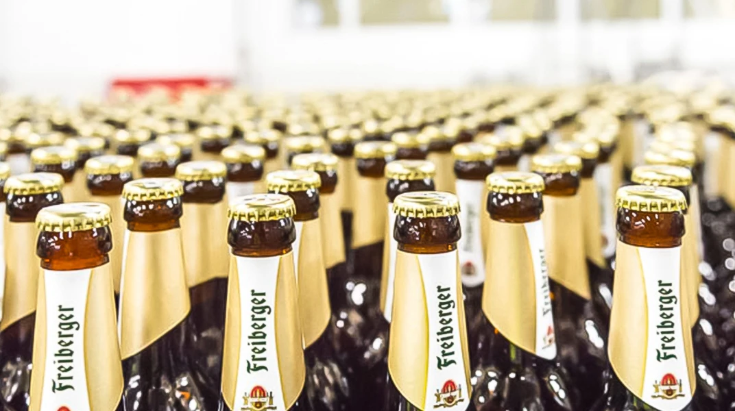 Reihen von Bierflaschen stehen eng aneinander auf einer Oberfläche. Alle Flaschen sind verschlossen und teilweise etikettiert.