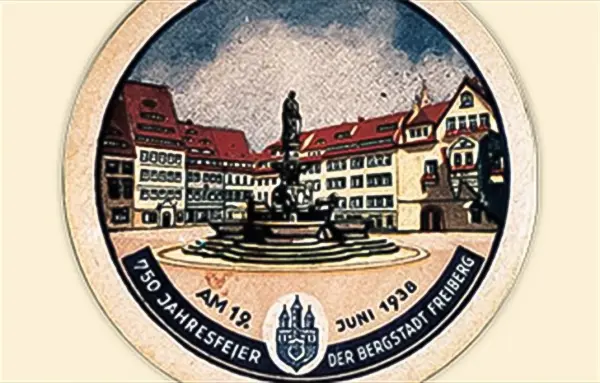 Ein historisches Gebäude und eine Statue auf einem Platz sind auf einer runden Medaille abgebildet.