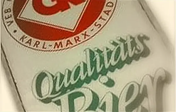 Ein Etikett mit rotem und grünem Text auf weißem Hintergrund zeigt Qualitätsmerkmale eines Produkts.