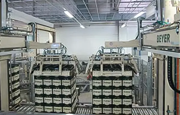 Mehrere Transportwagen sind in einer Industriehalle mit Kisten beladen.