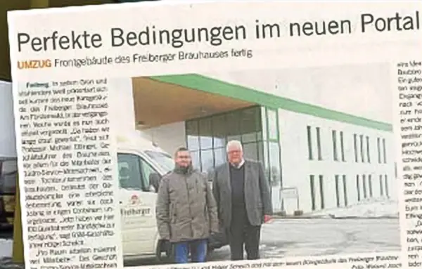 Zwei Männer stehen vor einem Gebäude mit grünem Vordach neben einem weißen Lieferwagen.