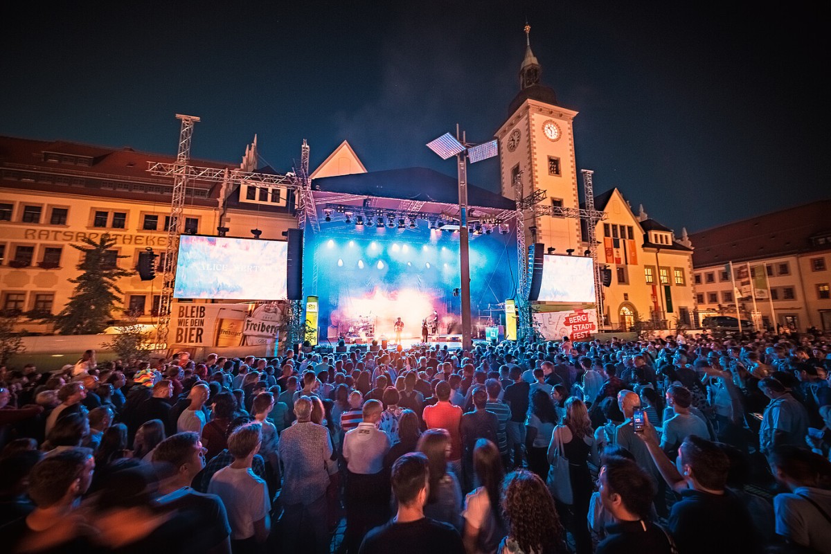 Eine große Menschenmenge steht vor einer Bühne, auf der eine Band ist.